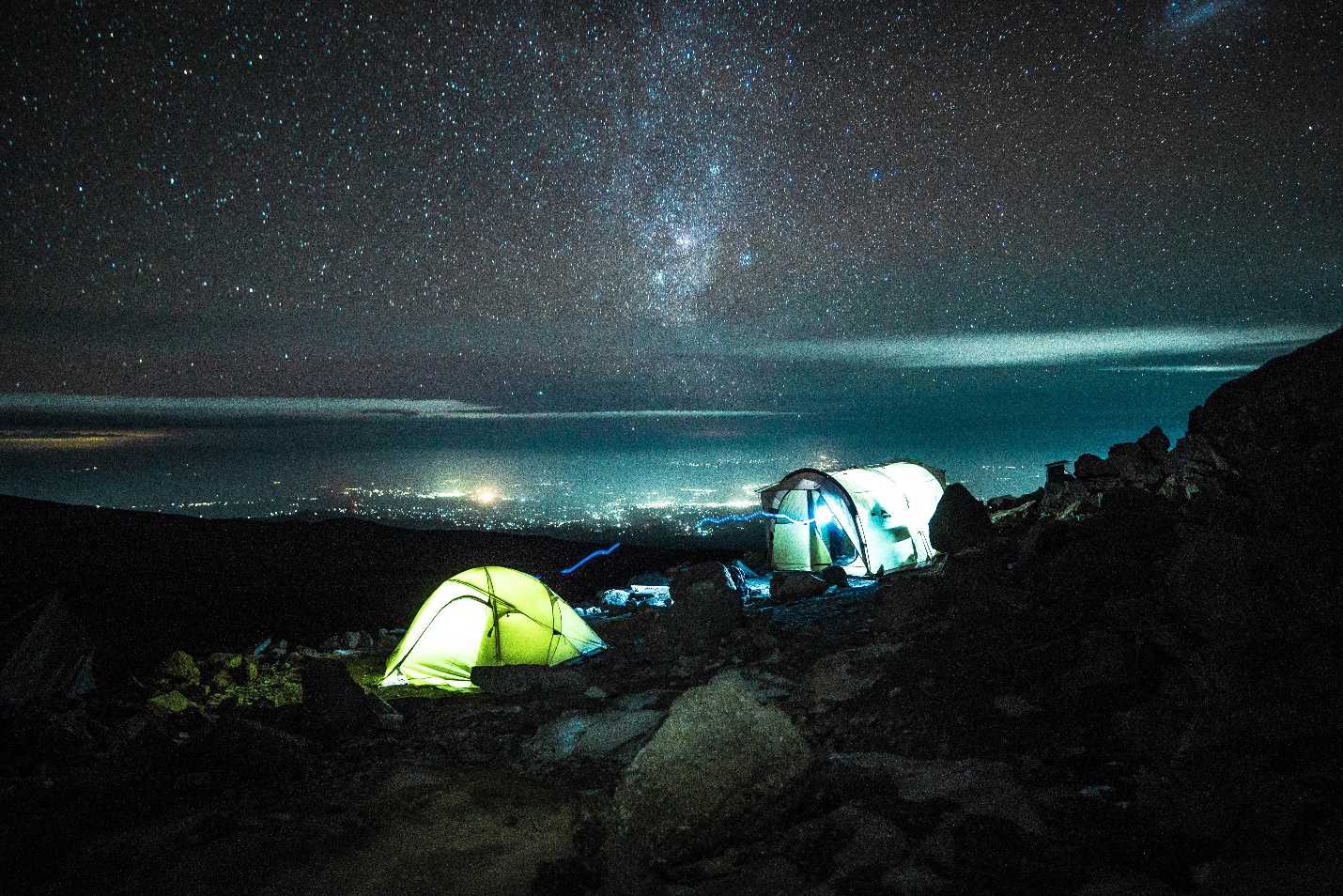 A safari tent lit from within at night at the base of Mt. Kilimanjaro.