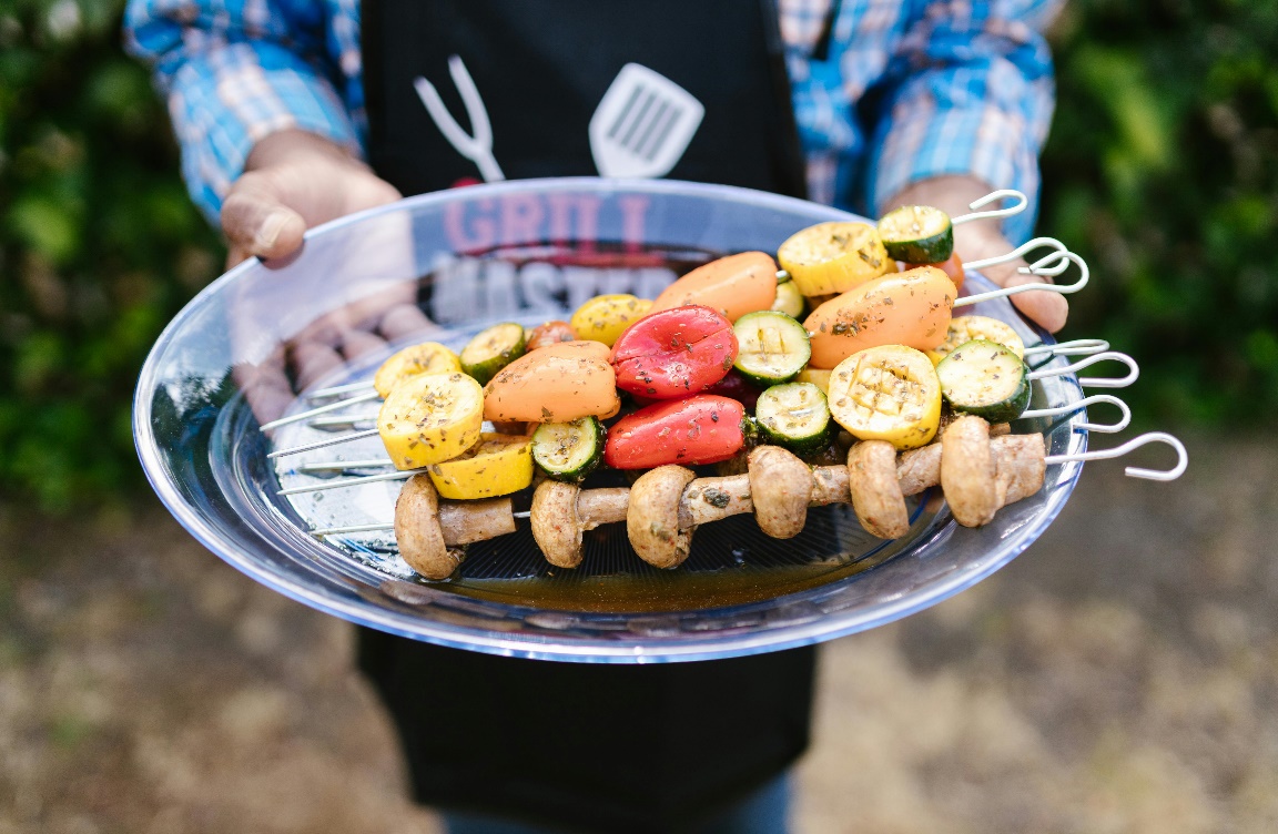 A man holding a plate with vegetable skewers.